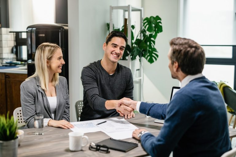 Happy couple shaking hands with their real estate agent at home